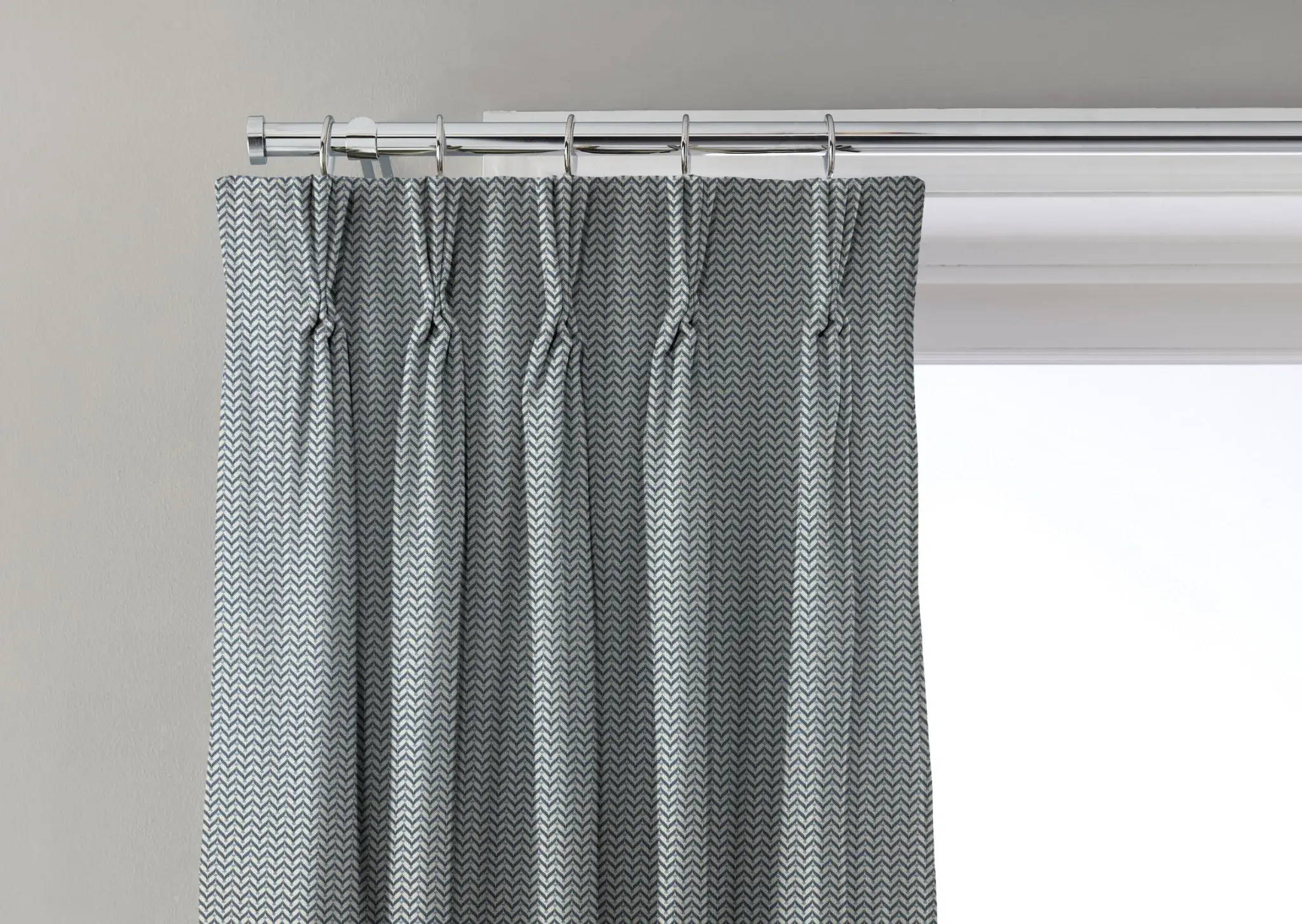 Curtain with a triple pinch pleat heading fitted to rings on a pole