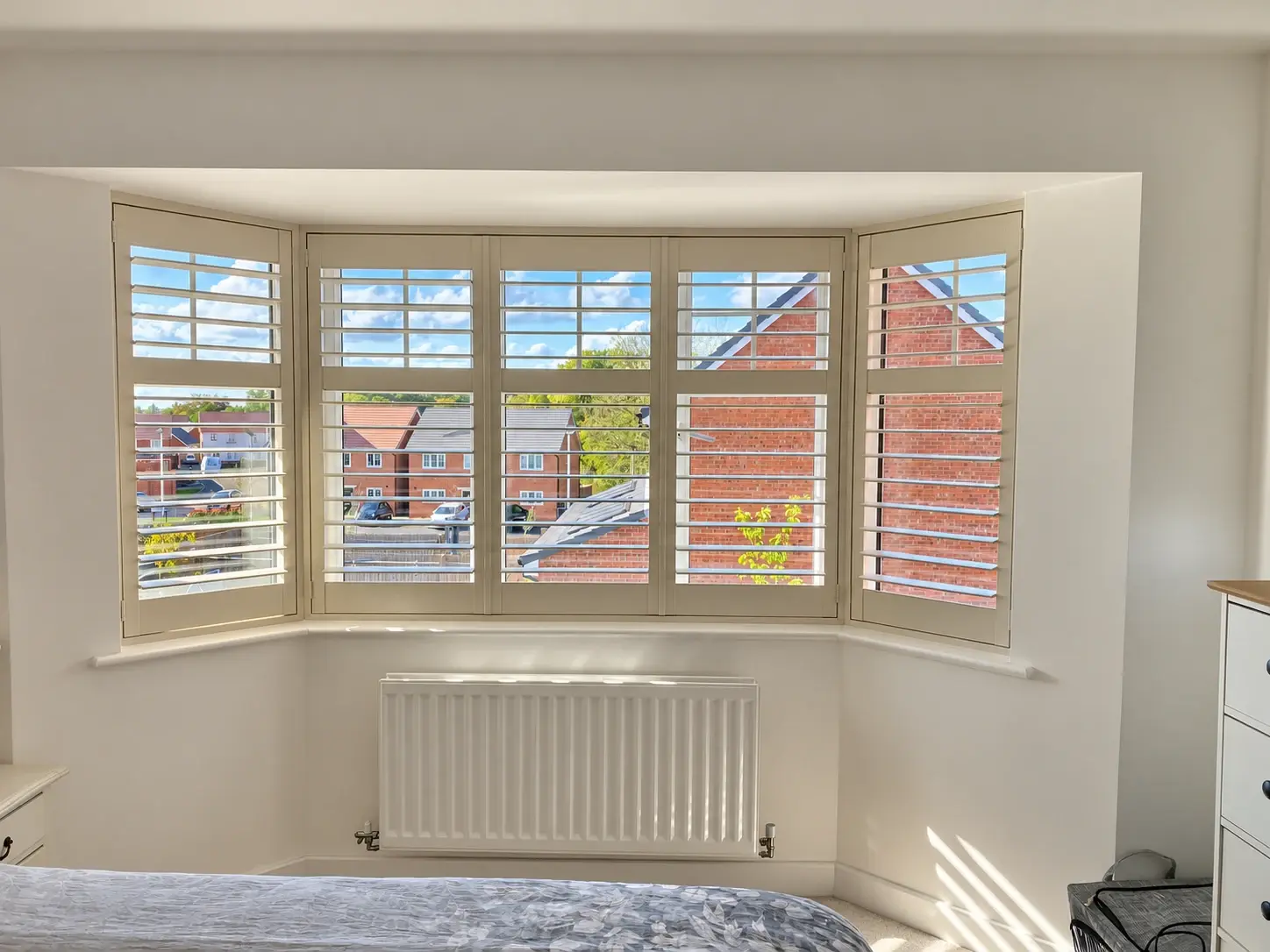 Ivory full-height shutters with open louvres across the upstairs bedroom bay window