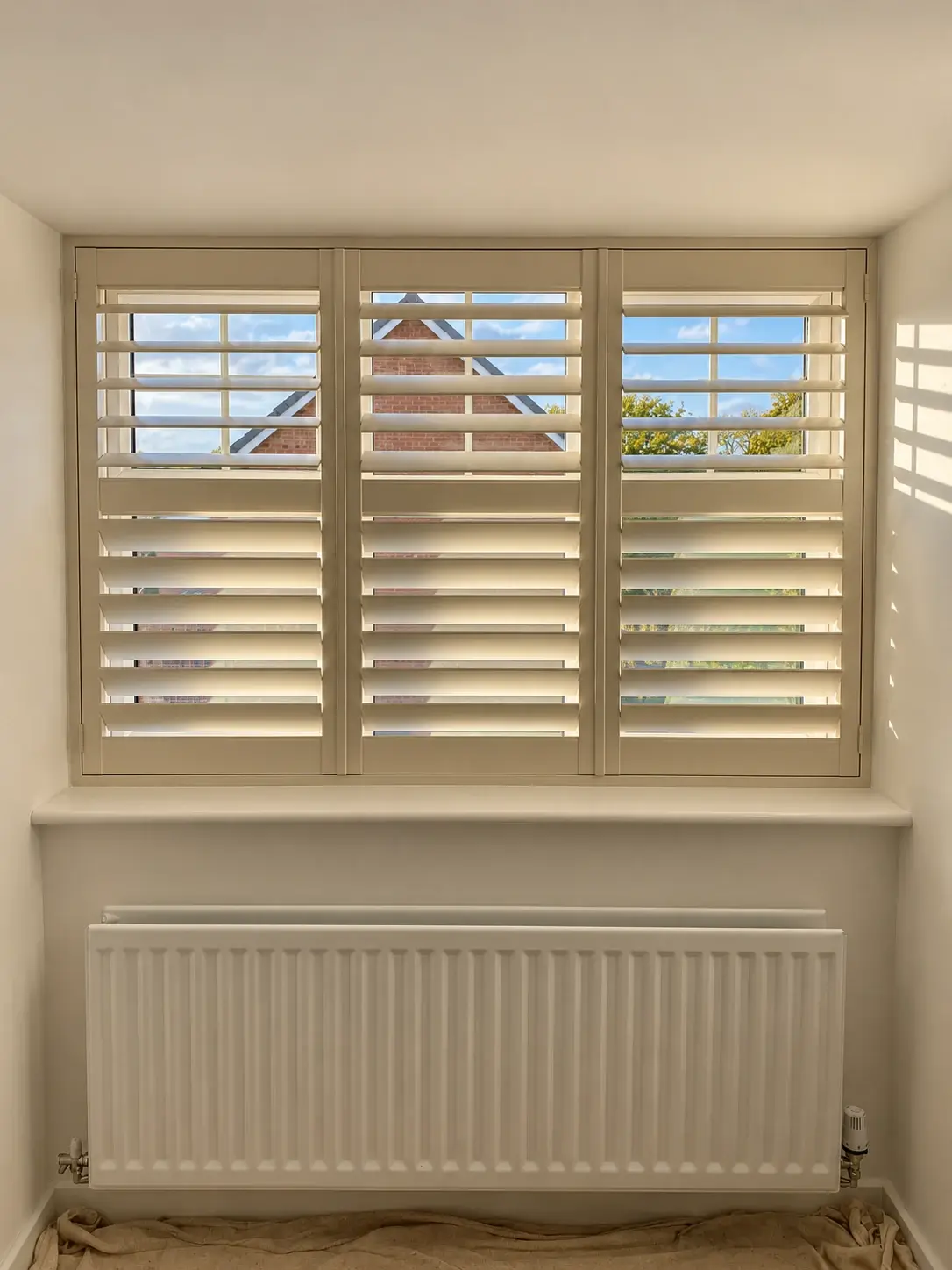 Three full-height Ivory Paulownia shutter panels with midrails at the second bedroom window