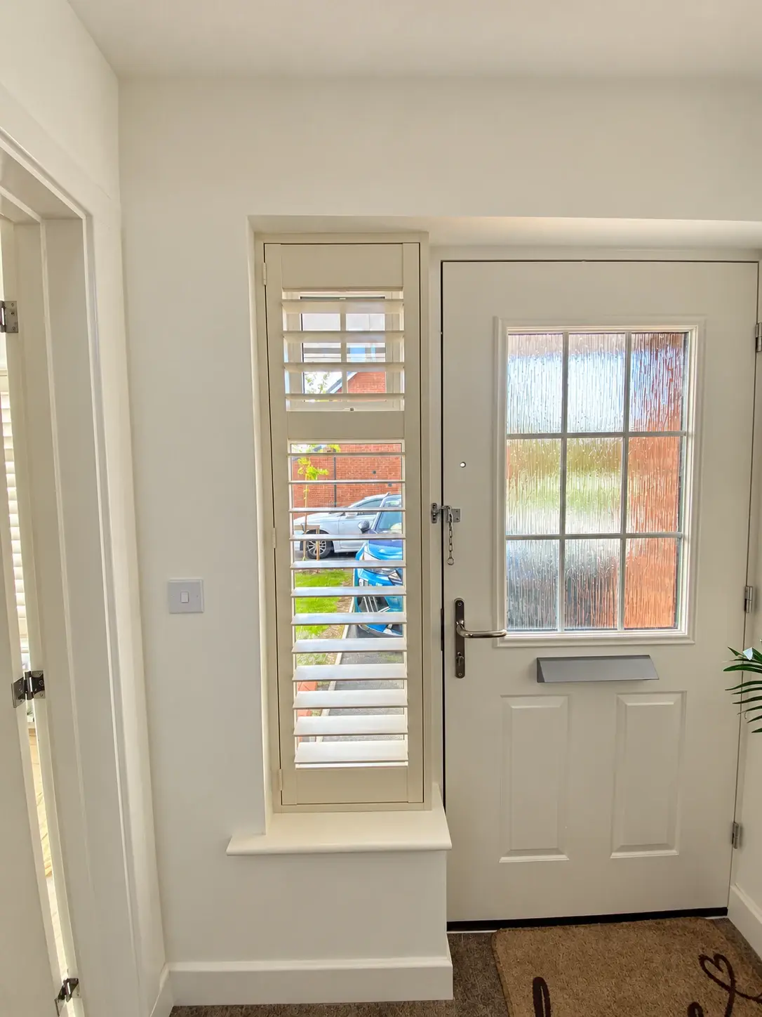 Narrow Ivory wooden shutter with a midrail fitted beside the entrance door