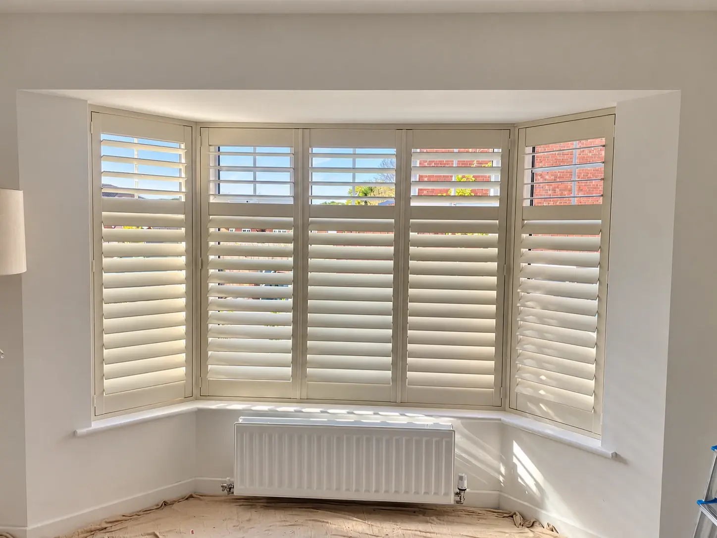 Living-room bay shutters with the lower louvres tilted towards closed and upper louvres open