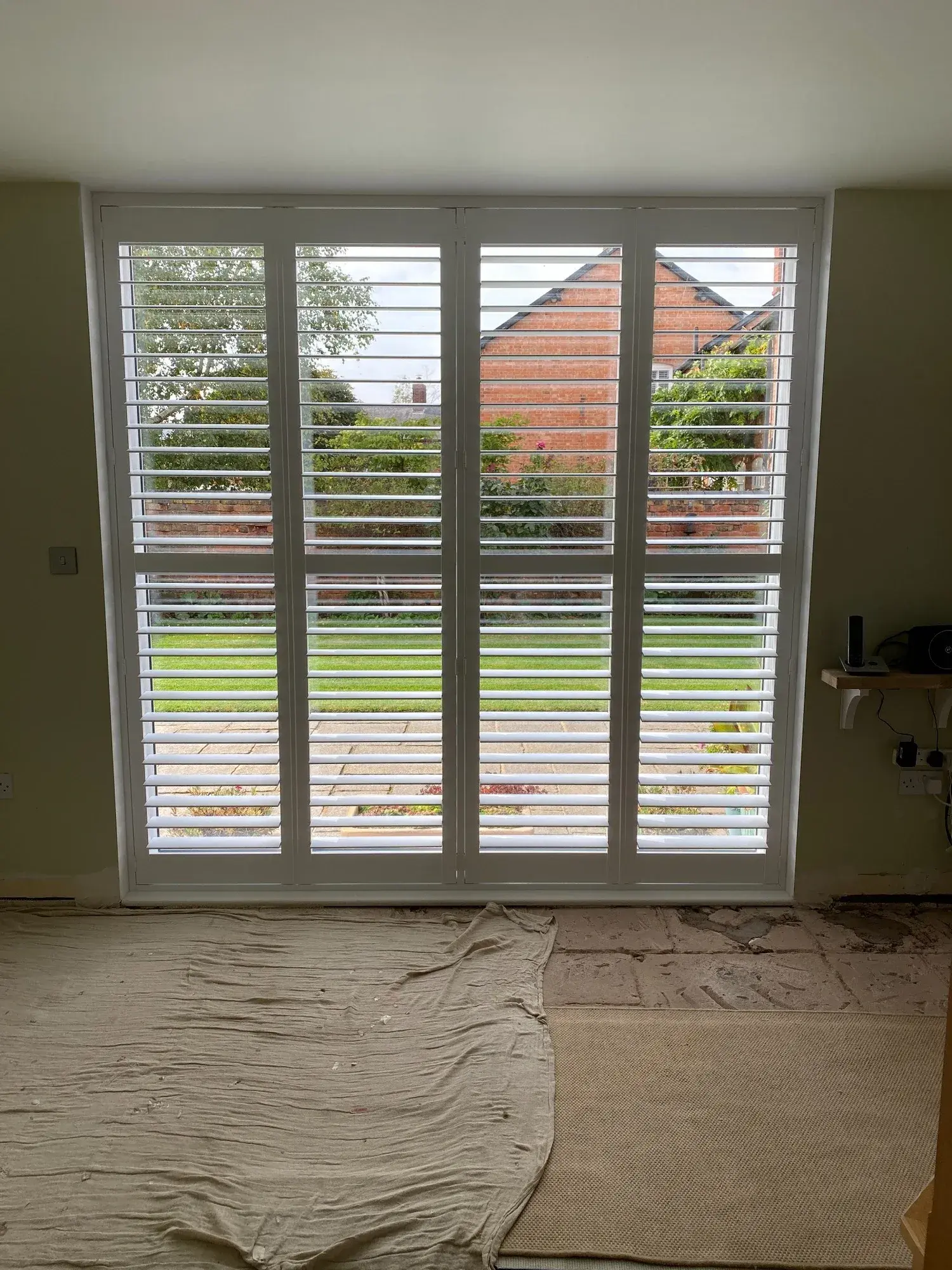 Pure White full-height wooden shutter panels fitted across the tall entrance glazing