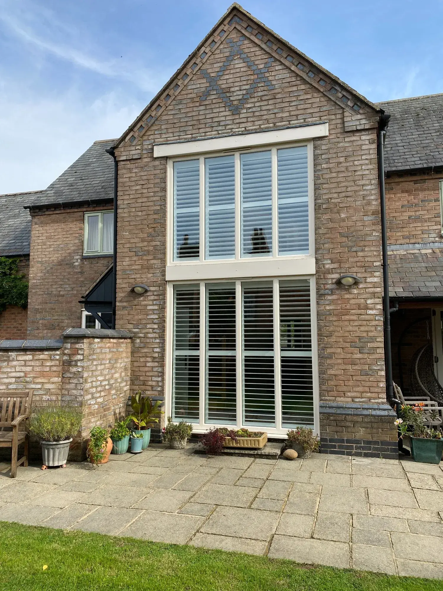 Pure White wooden shutters seen from outside the tall entrance and upstairs windows in Lutterworth