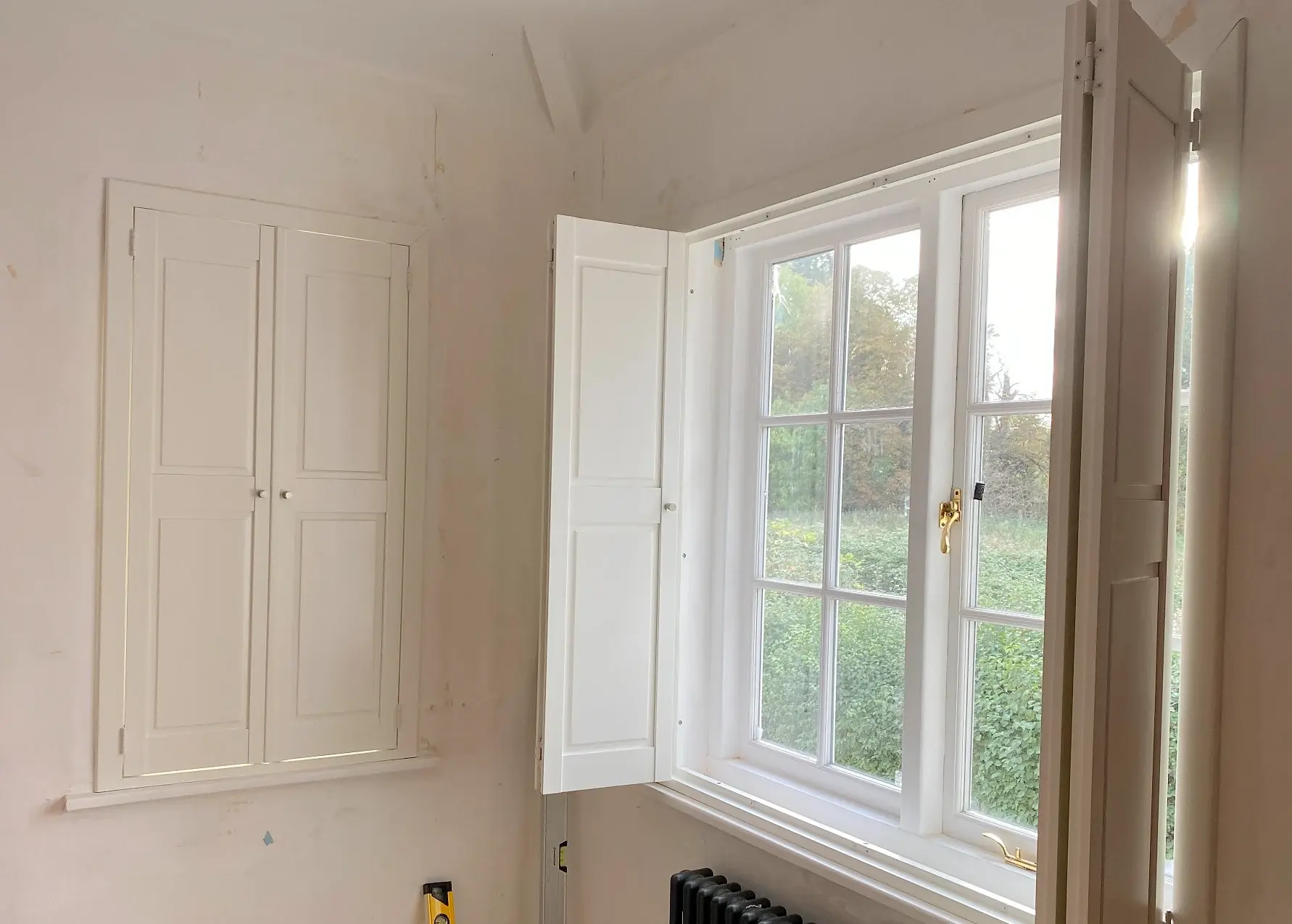 Silk White solid panel shutters with a narrow window closed and adjacent wider window open