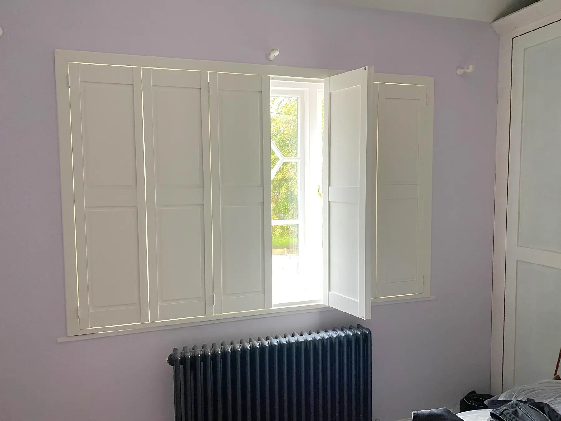 Partially open Silk White solid panel shutters in Market Harborough