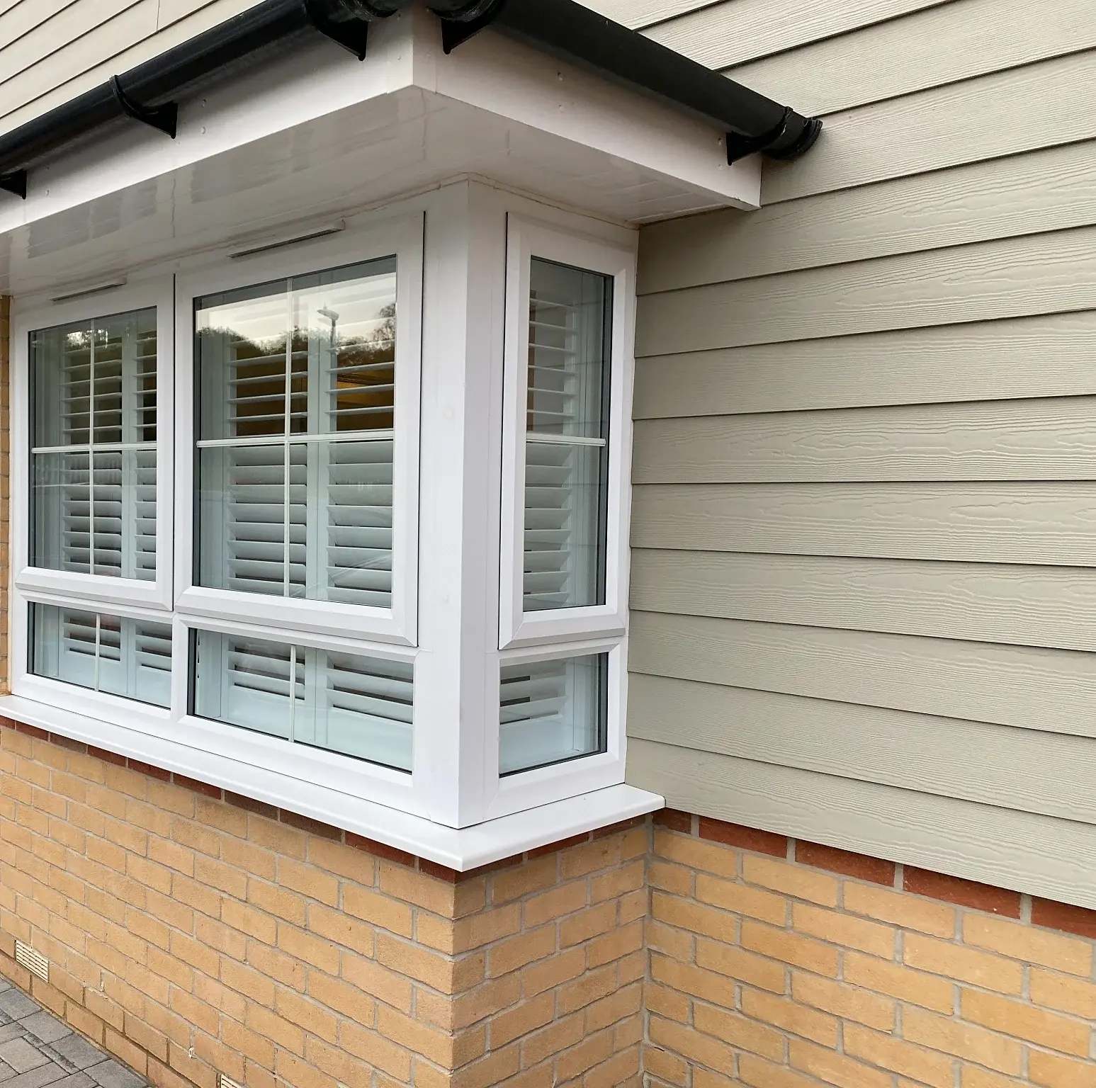 Full-height shutters with 63 mm louvres in Wellingborough: The bay-window installation viewed from outside.