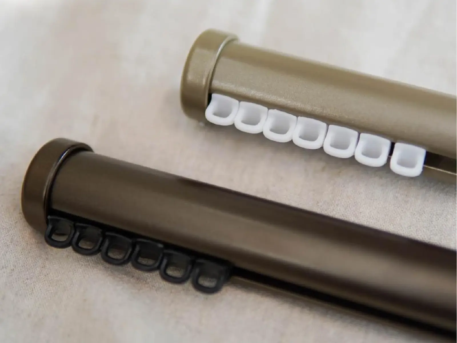 Two premium tracked curtain poles shown in different metallic finishes