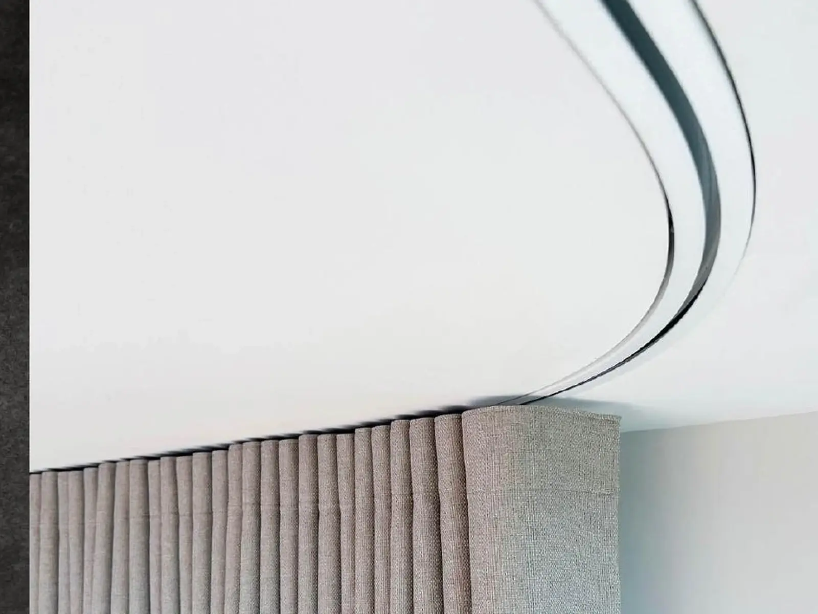 A motorised curtain track recessed into a ceiling above pleated curtains for a concealed finish