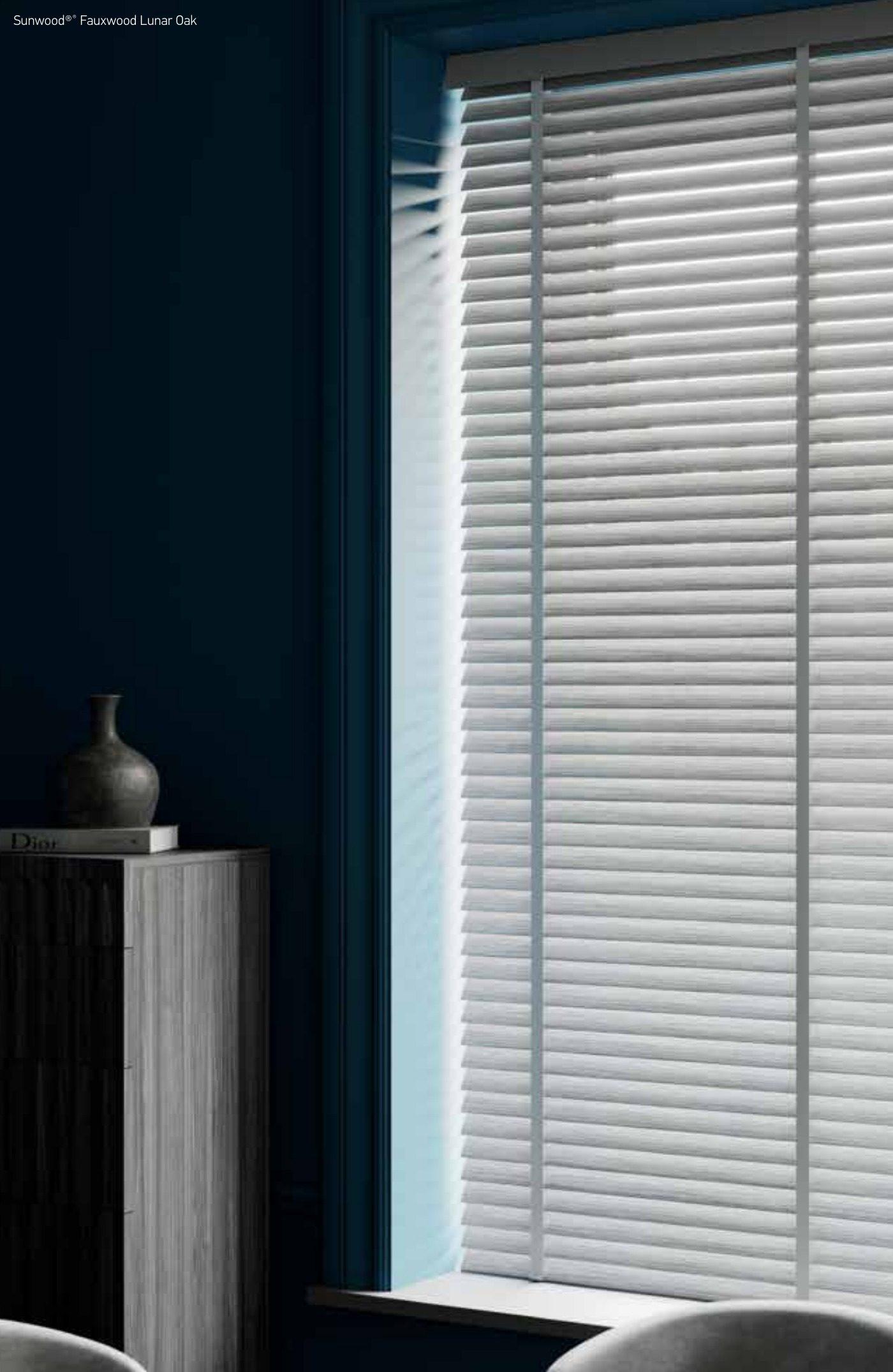 Close-up of white and silver aluminium venetian slats with light streaming through and ladder cords visible