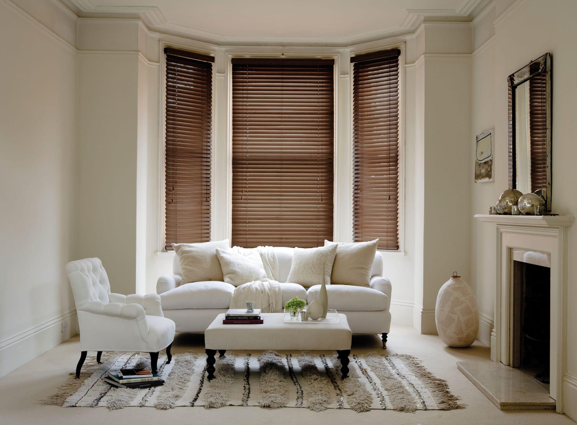 Dark walnut wooden venetian blinds across a bay window in a period living room
