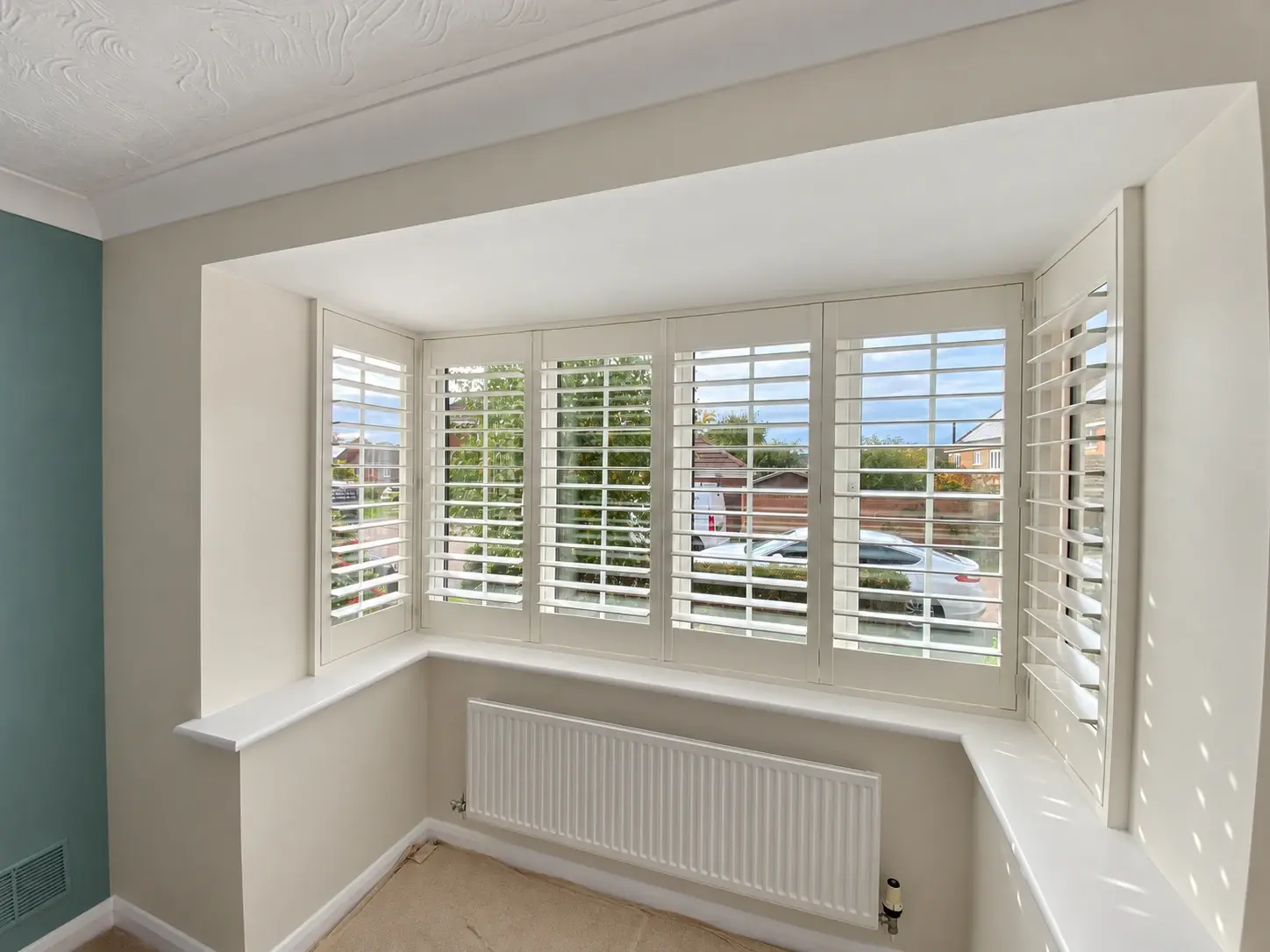 Silk White full-height wooden shutters following the right-angle returns of the box bay